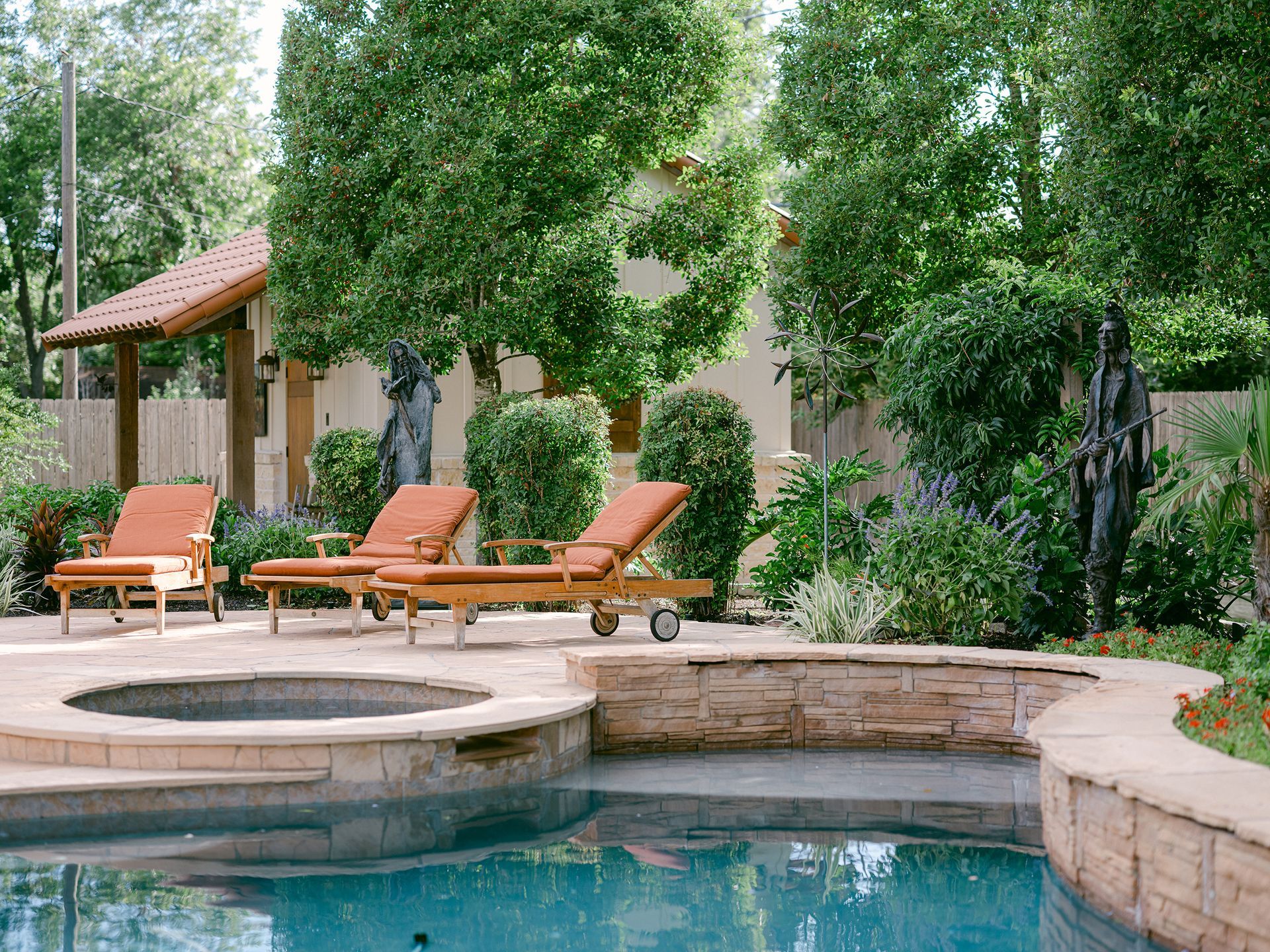 A swimming pool with a hot tub and lounge chairs around it