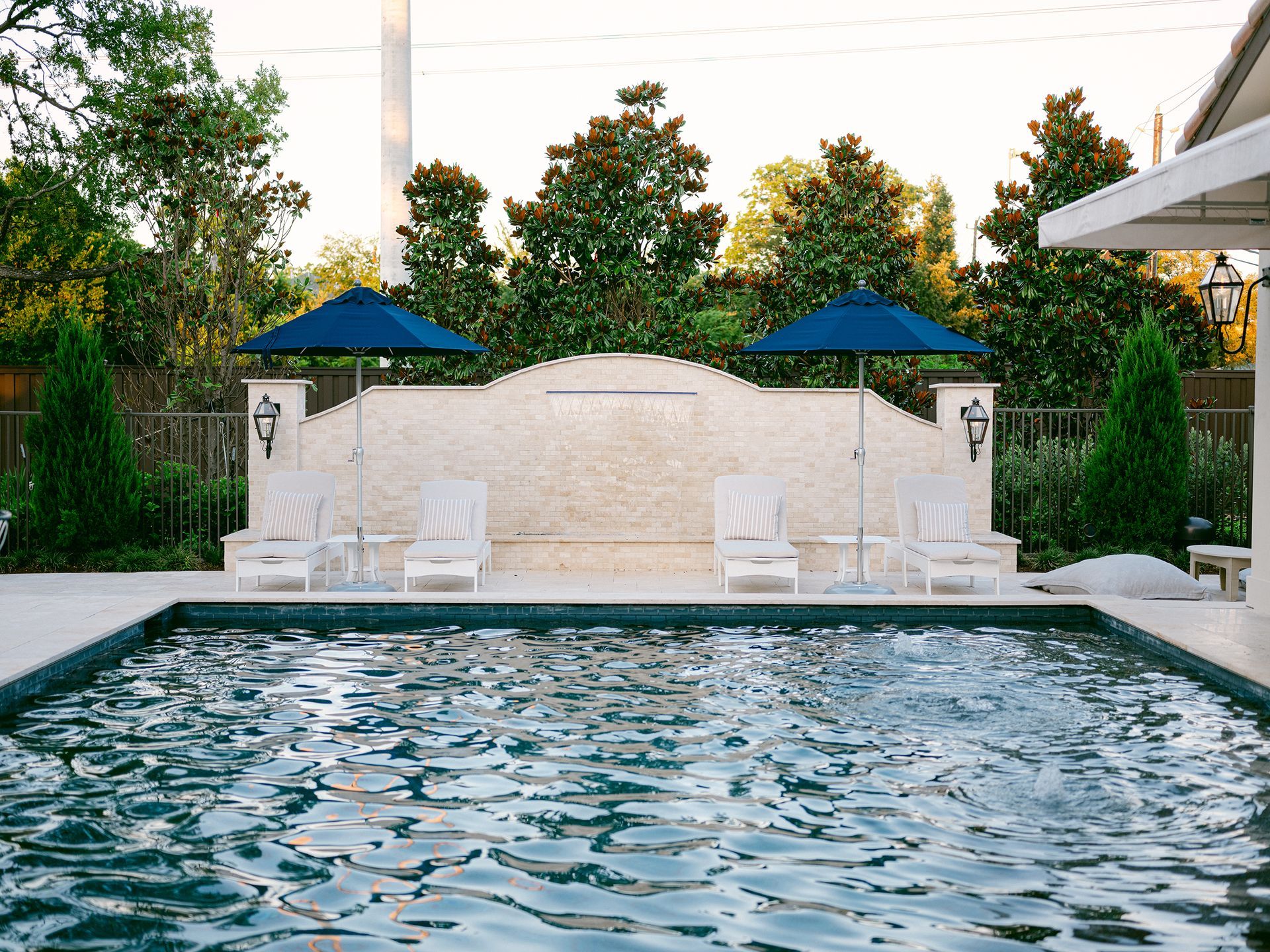 A large swimming pool surrounded by chairs and umbrellas