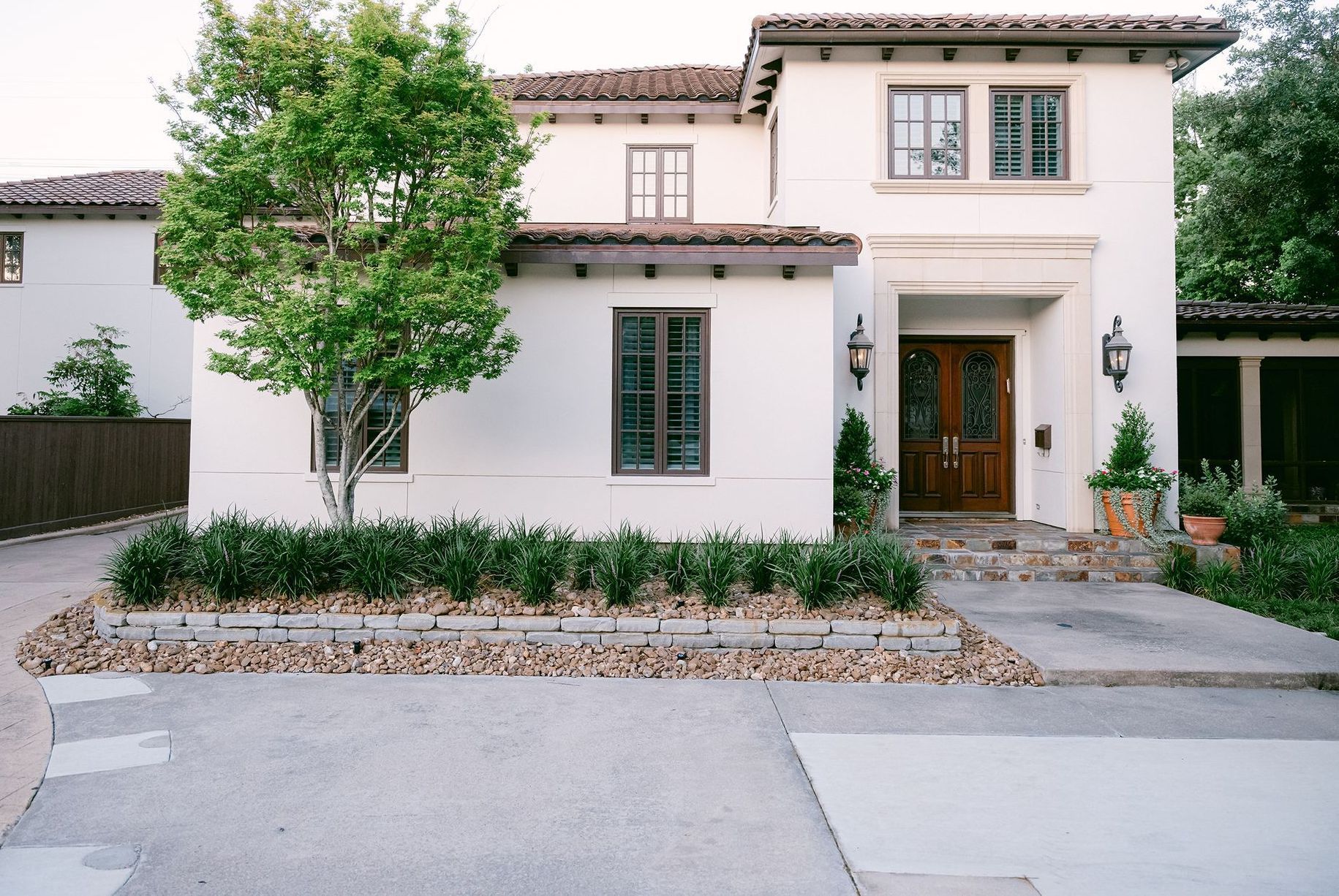 A white house with a tree and nice landscaping in front of it