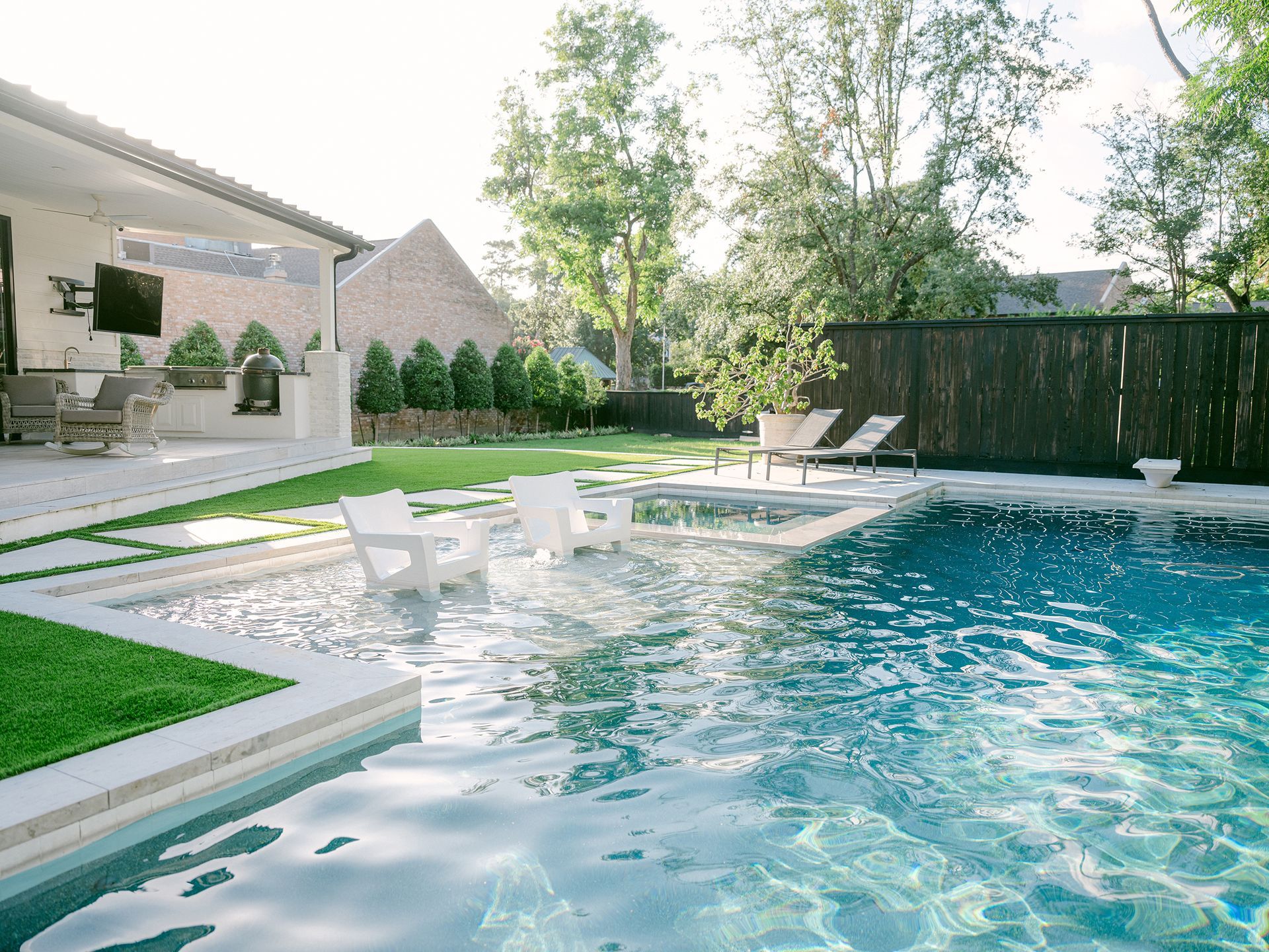 There is a large swimming pool in the backyard of a house.
