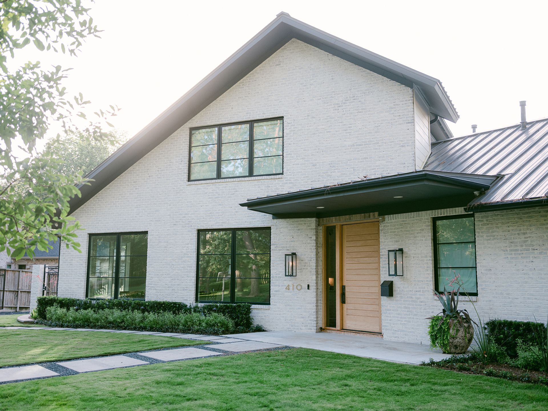 A white brick house with a metal roof and a wooden door.