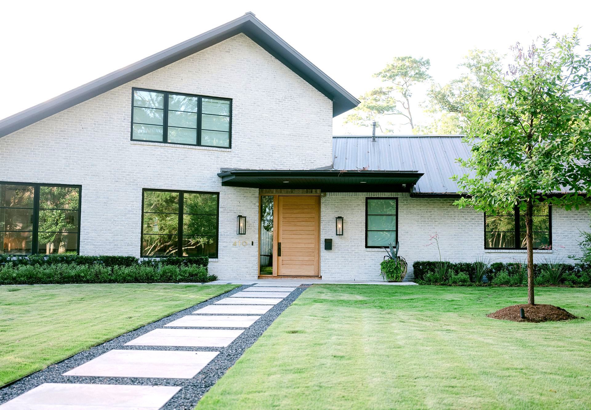 A large white house with a wooden door and a walkway leading to it.
