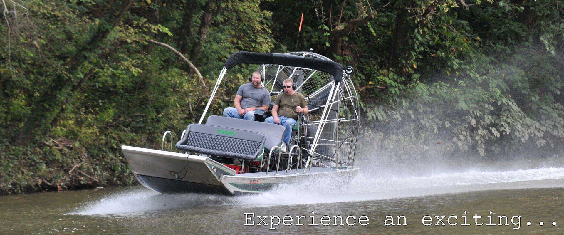 White-water airboat speeding through a river, spraying water, with passengers onboard in a forested setting