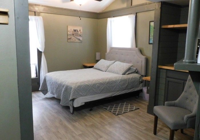 Cozy bedroom with a gray bed, chair, window light, and wood flooring