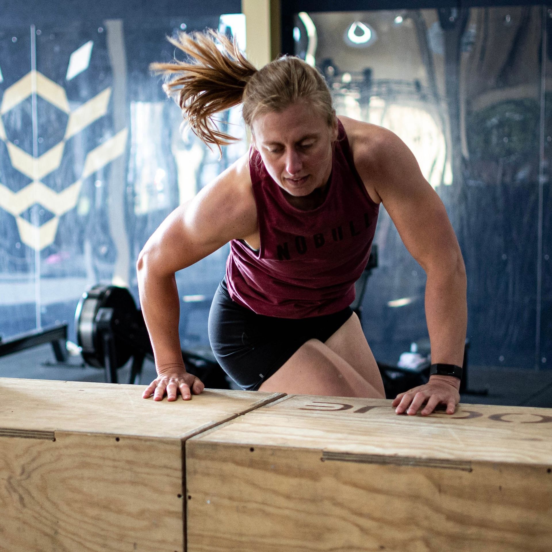 Een vrouw in sportkleding leunt op een houten kist, klaar om erop te stappen.