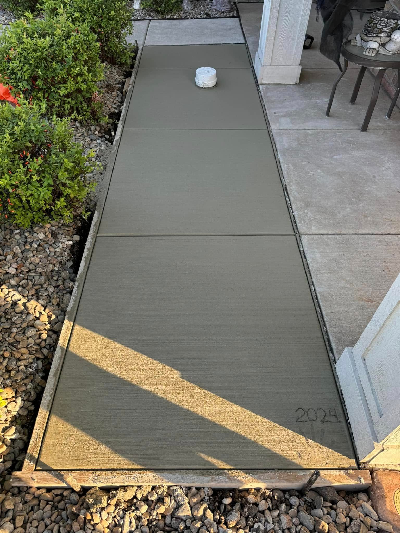 A newly poured concrete walkway with visible joint lines, 