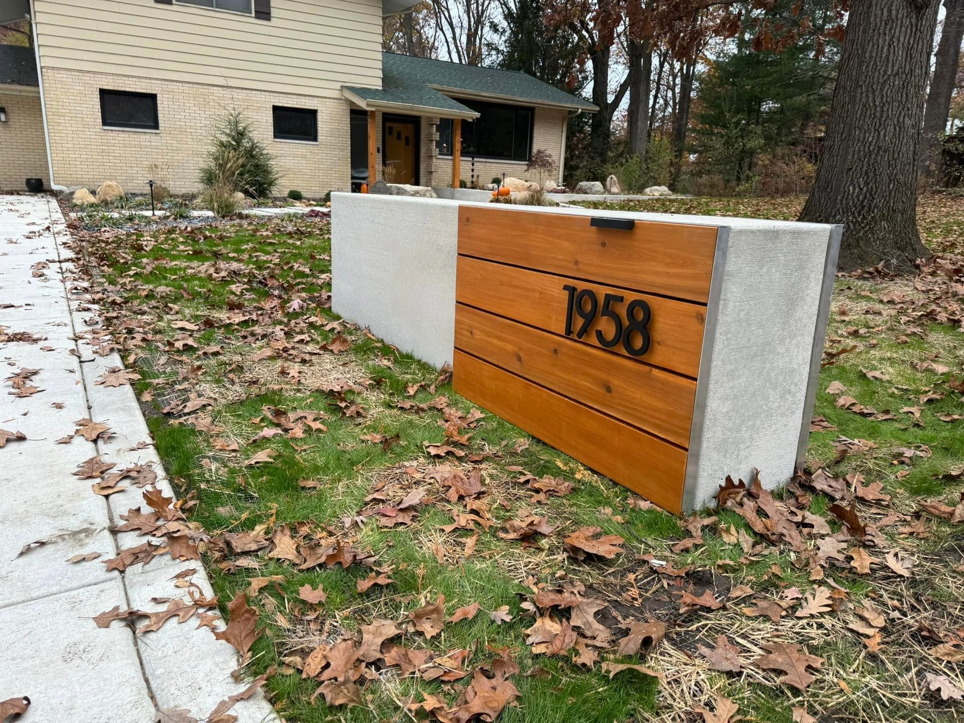 A low concrete and horizontal wood-slat house number sign labeled 