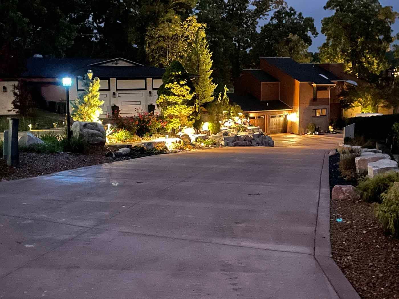 A concrete driveway leading to a house at night