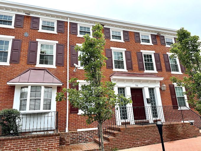 A large red brick building with white trim and brown shutters.