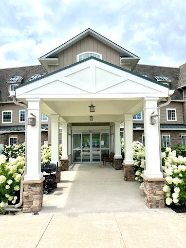 A large building with a porch and flowers in front of it.
