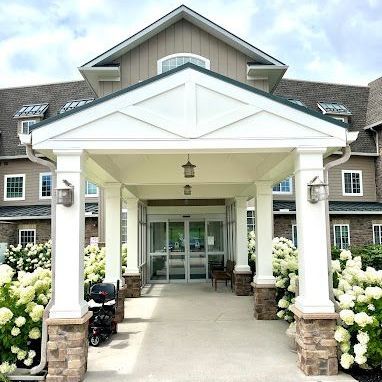 A large building with a white porch and flowers in front of it.
