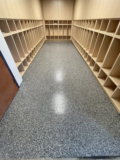 A locker room with lots of shelves and a gray floor.
