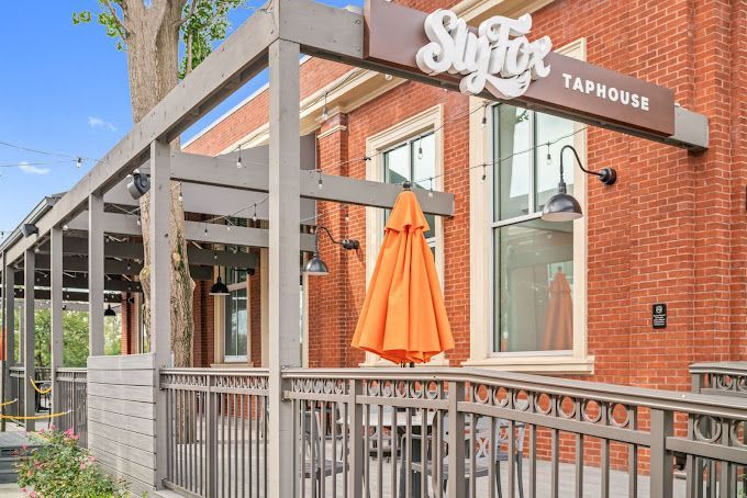 A brick building with a fence and an orange umbrella in front of it.