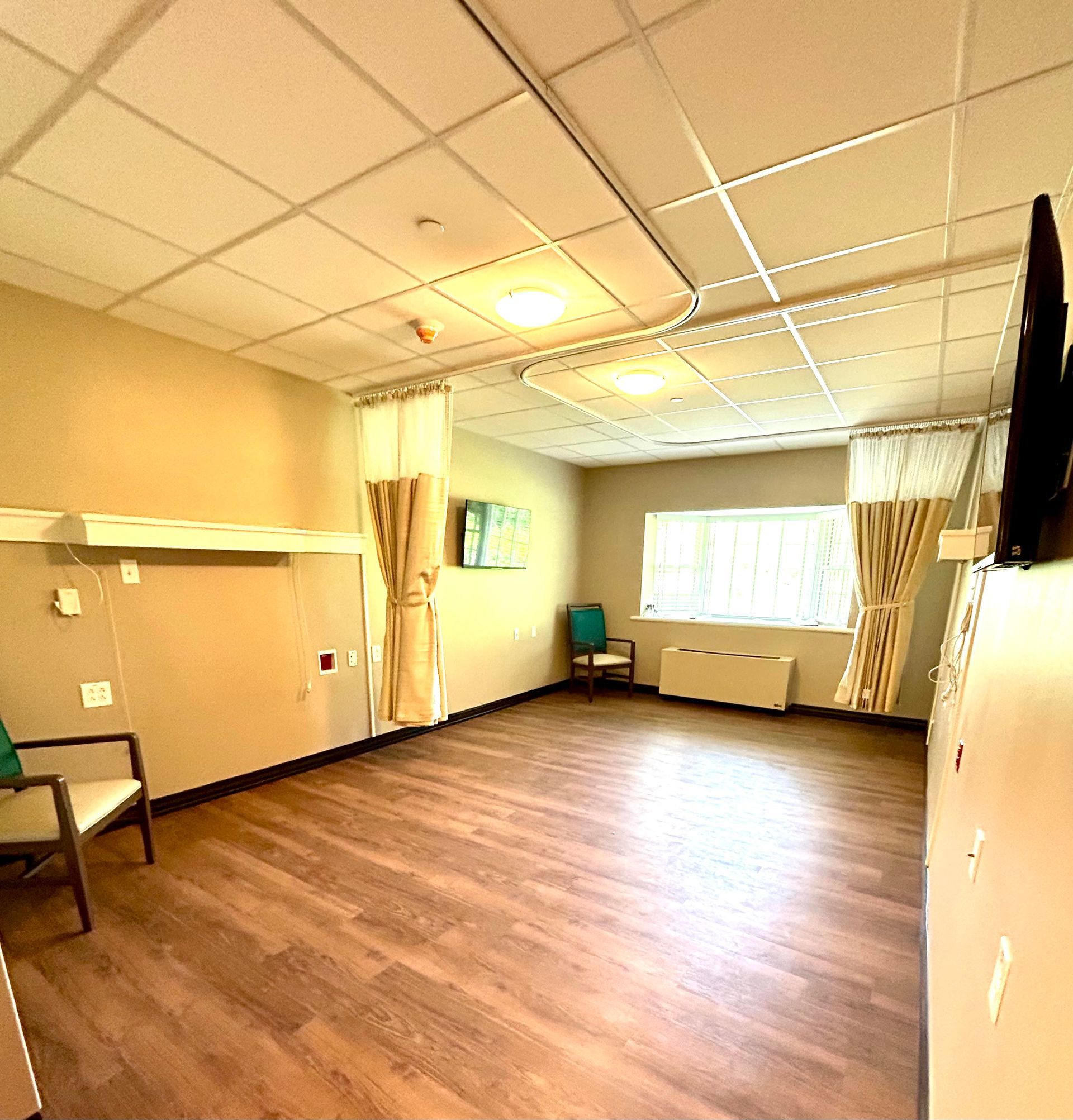 A large empty room with wooden floors and a chair.
