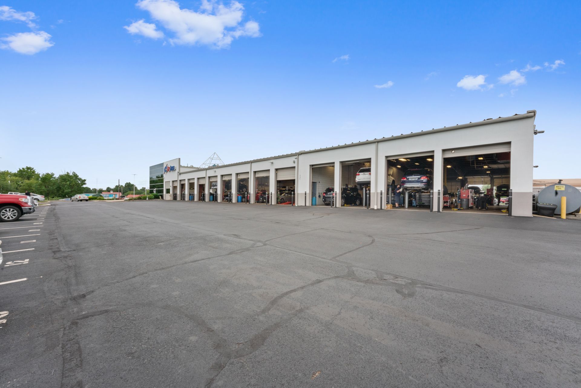 A row of cars are parked in front of a large garage.