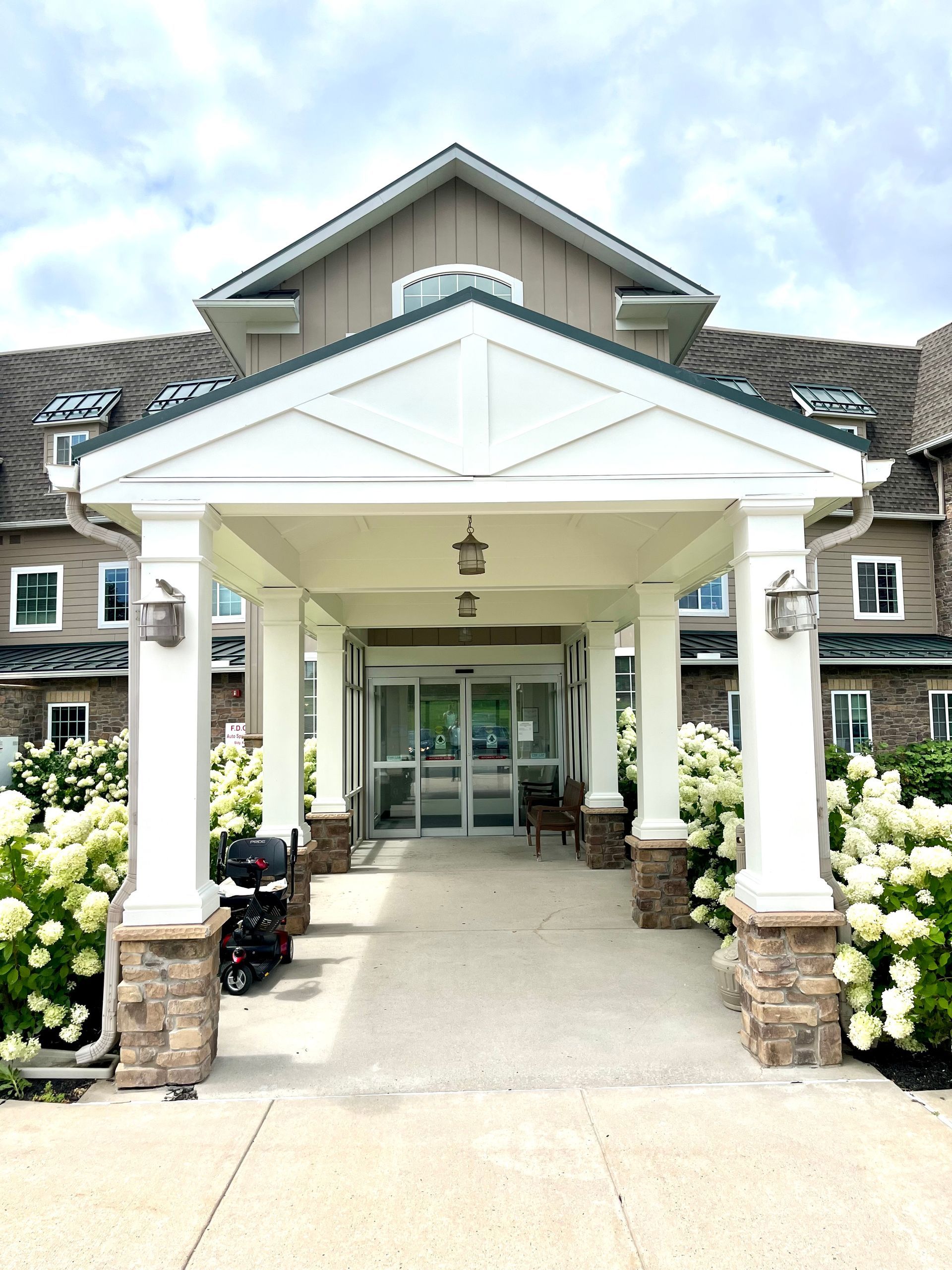 A large building with a porch and flowers in front of it