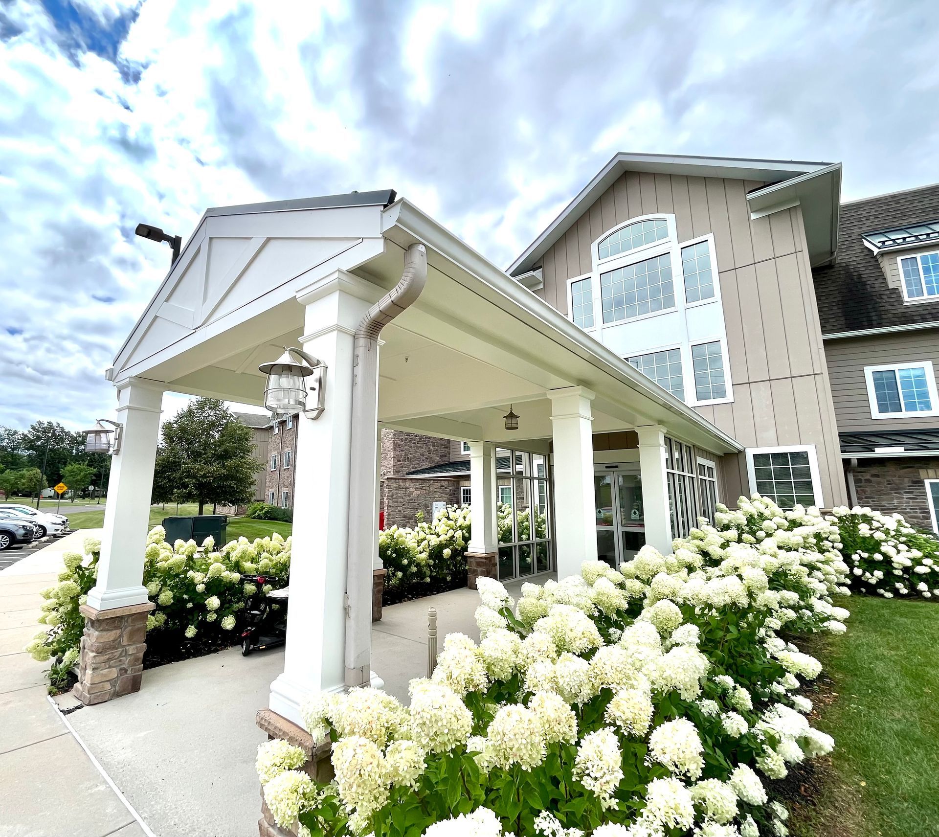 A large house with a porch and flowers in front of it