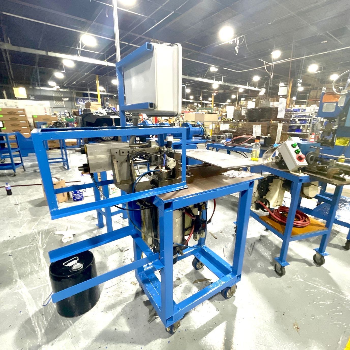 A machine is sitting on top of a blue cart in a factory.