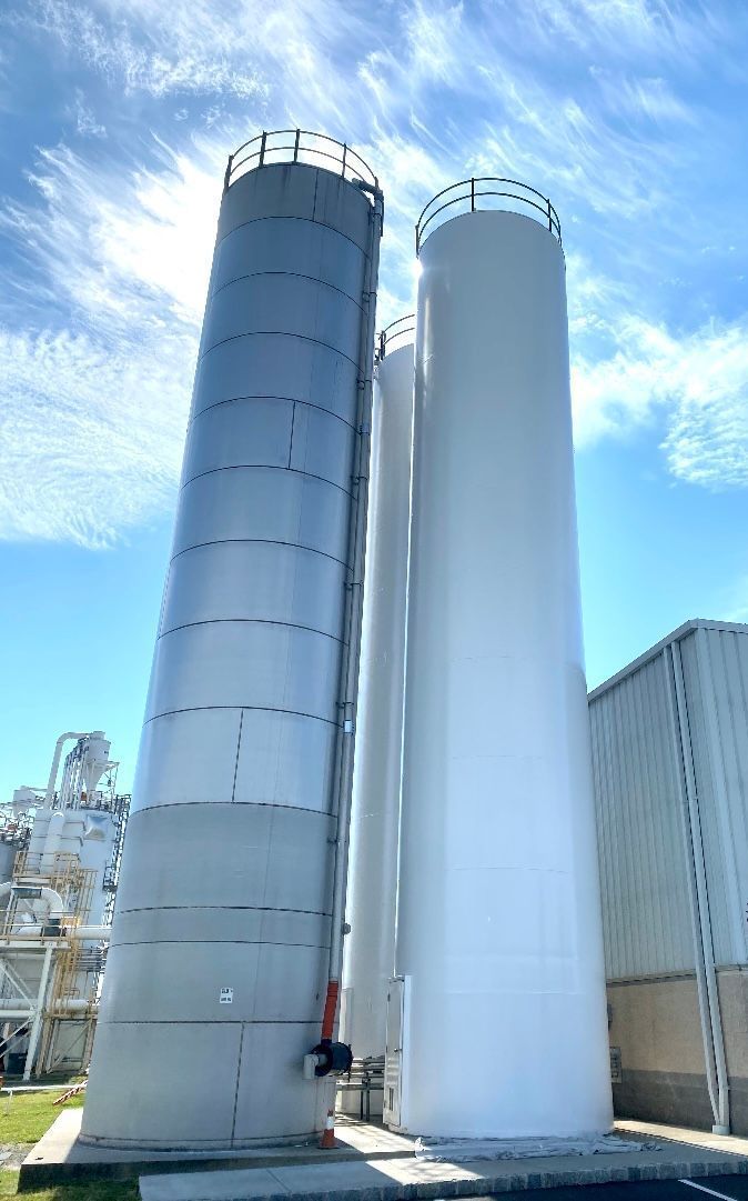 Two large white silos are sitting next to each other in front of a building.