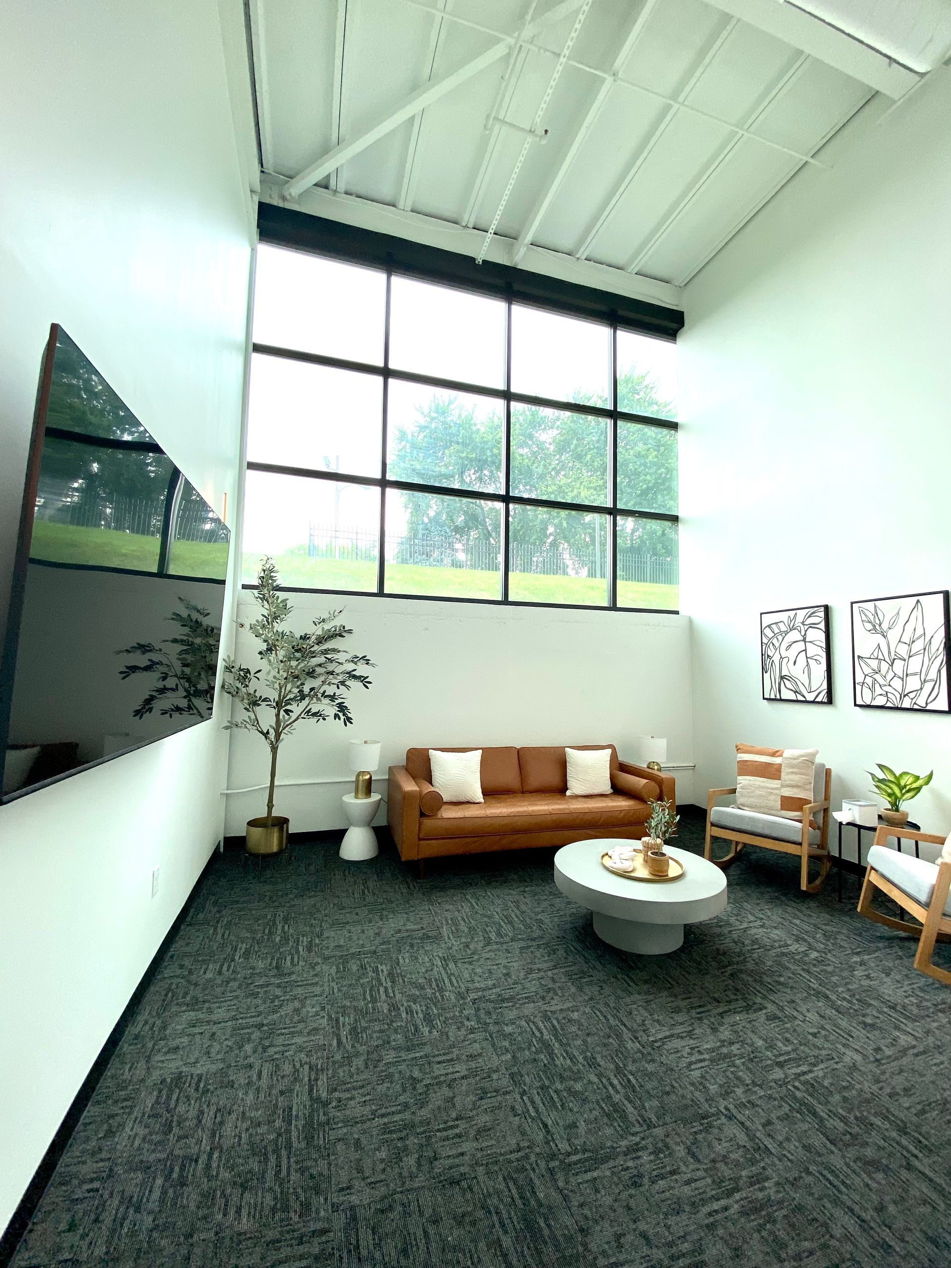 A living room with a couch , chairs , a coffee table and a large window.