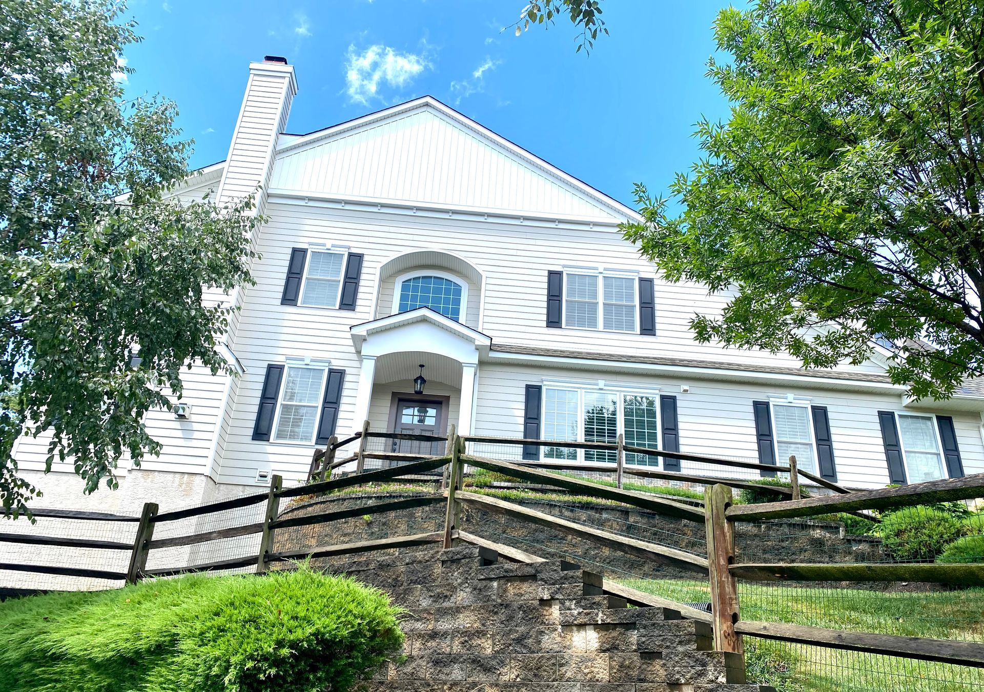 A large white house with a wooden fence in front of it.