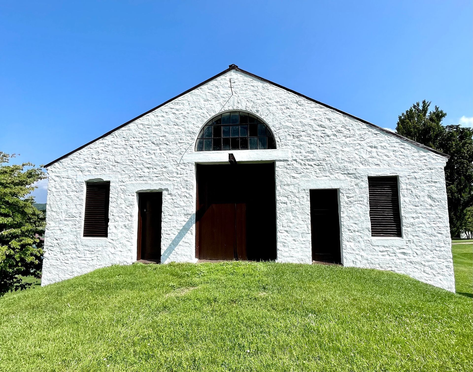 A white building is sitting on top of a grassy hill.