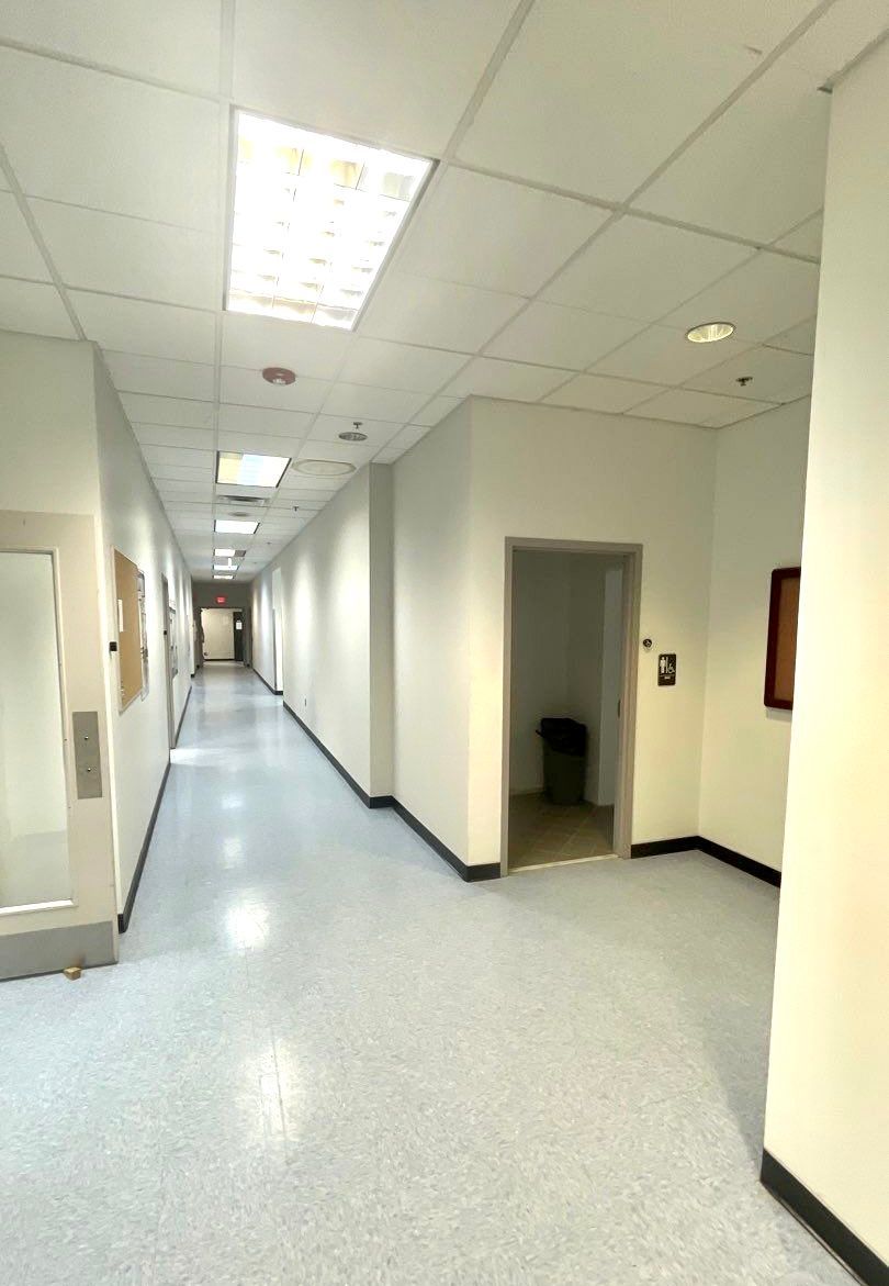 A long hallway with white walls and a door