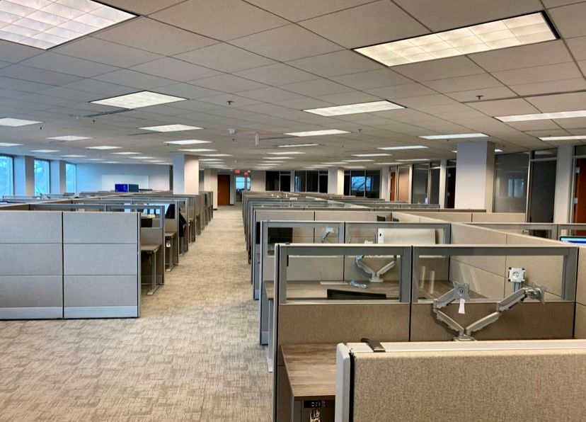 A large office with a lot of cubicles and a lot of windows.
