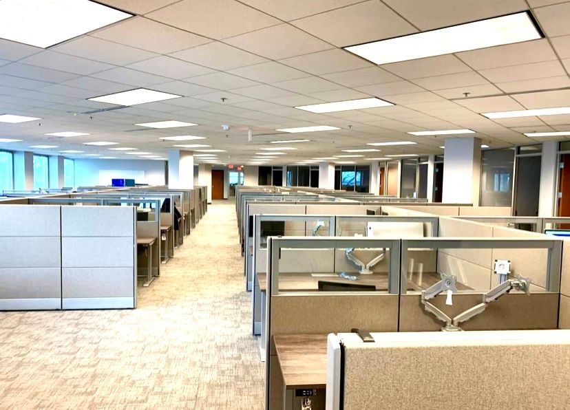 A large office with a lot of cubicles and a lot of windows