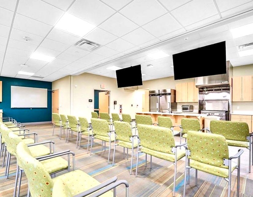 A large room with rows of chairs and televisions on the ceiling.