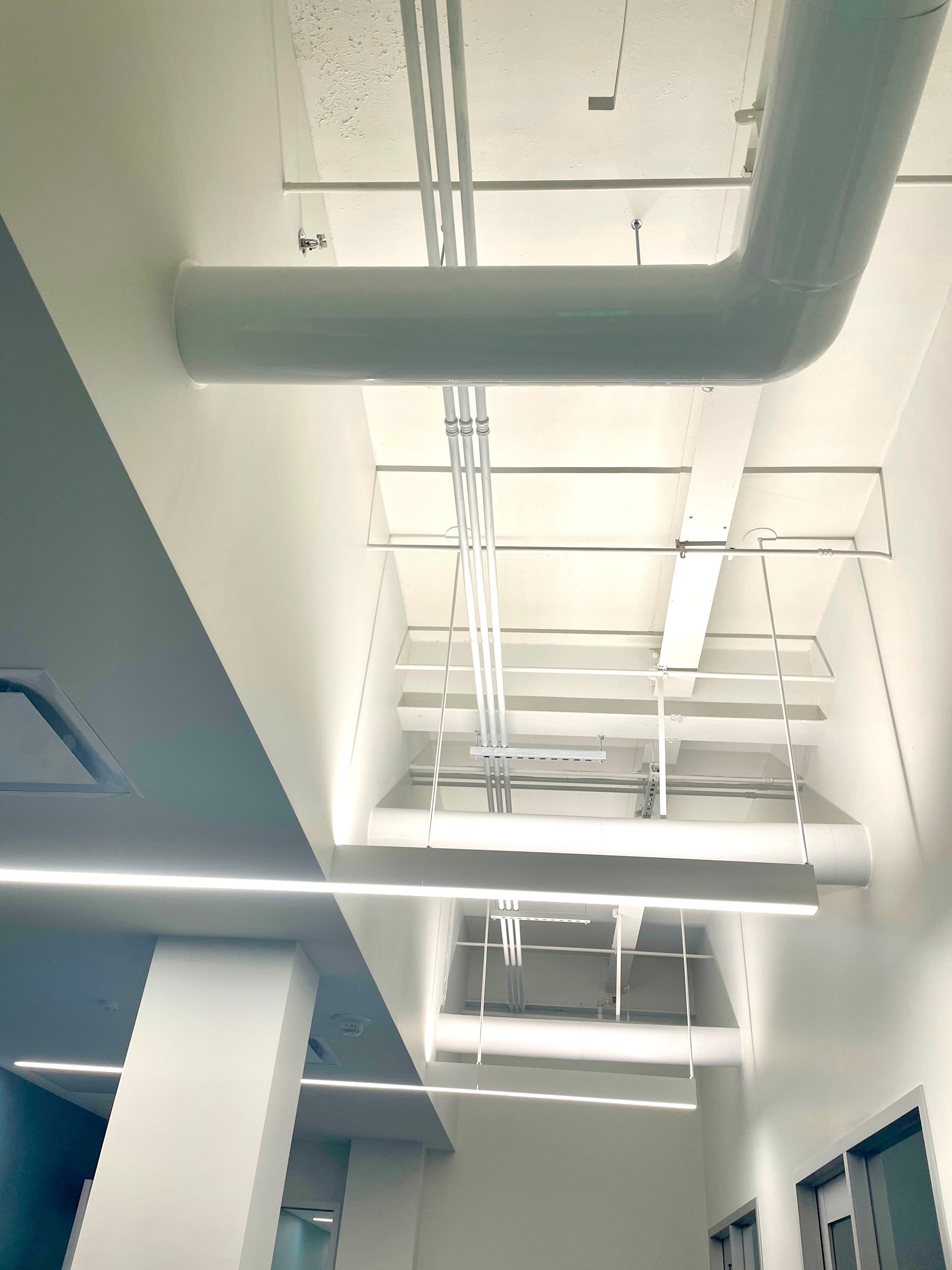 A hallway with a lot of pipes hanging from the ceiling