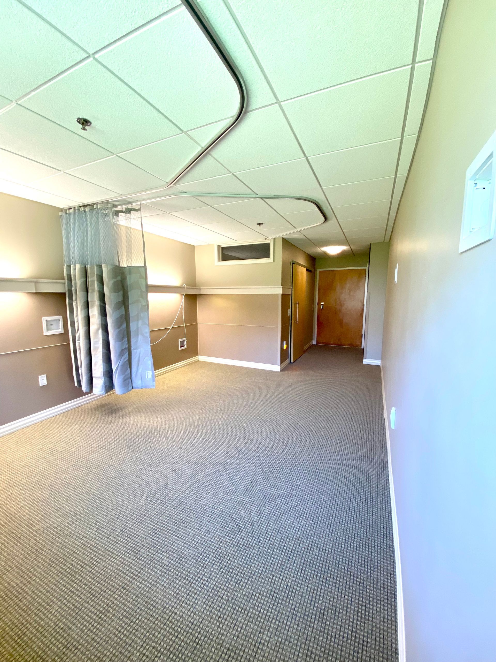 An empty hospital room with a curtain hanging from the ceiling.