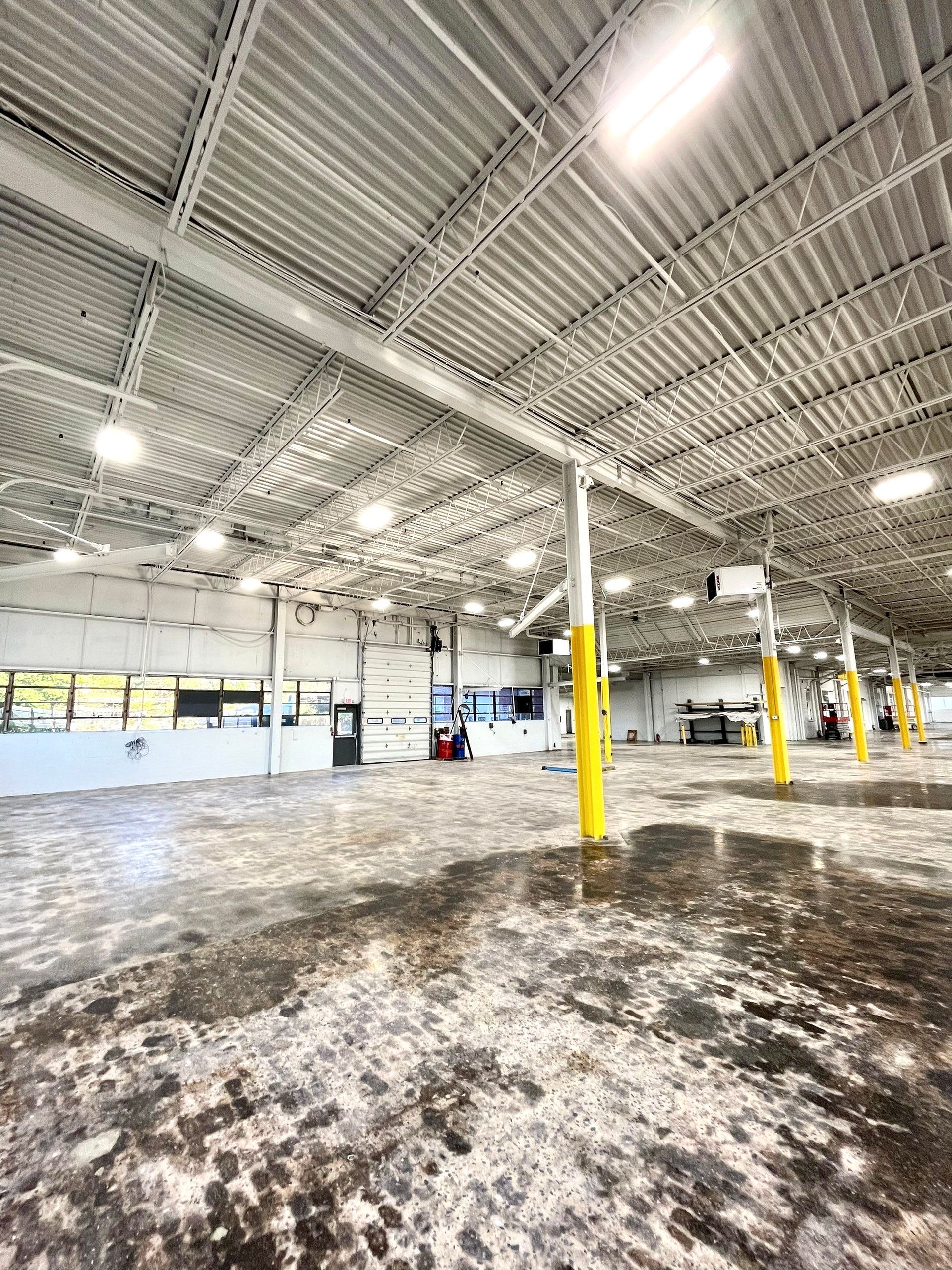 A large empty warehouse with a lot of lights on the ceiling.