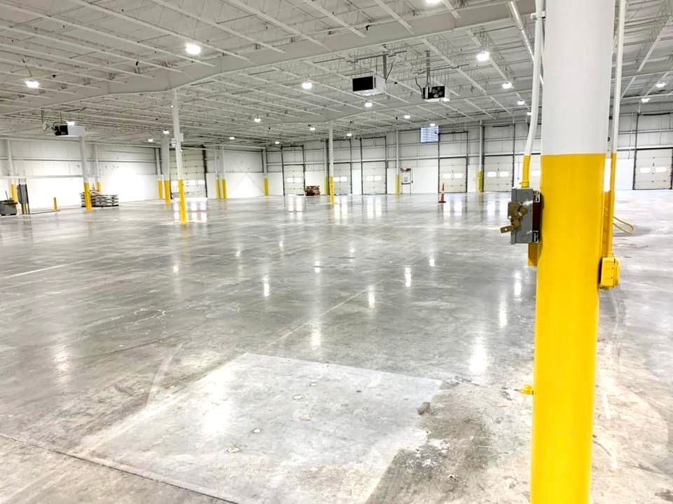 A large empty warehouse with concrete floors and yellow poles.
