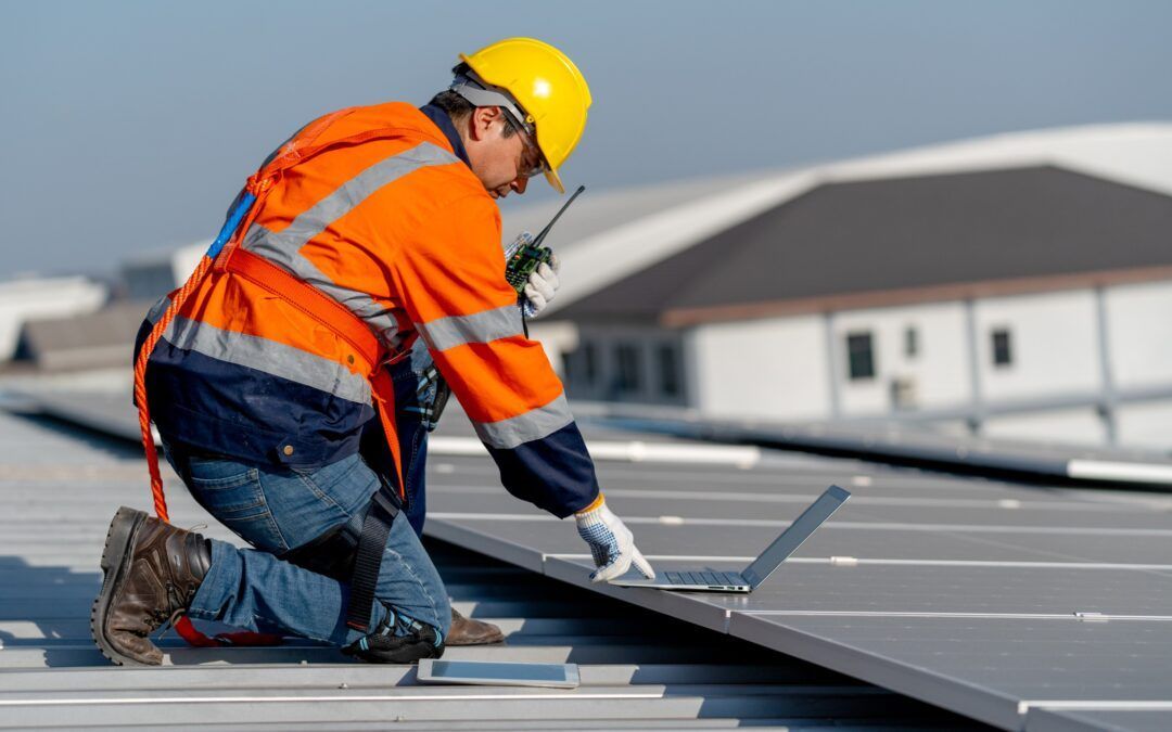 Professional roofer installing solar panels on commercial building roof with safety equipment.