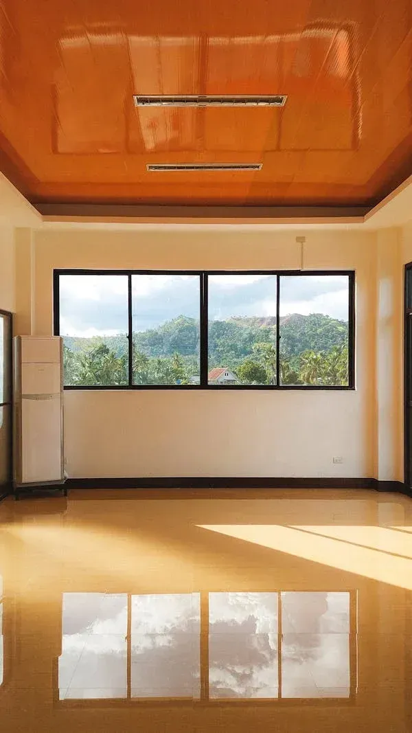 Elegant room with glossy polished concrete floors reflecting tropical mountain views through panoramic windows