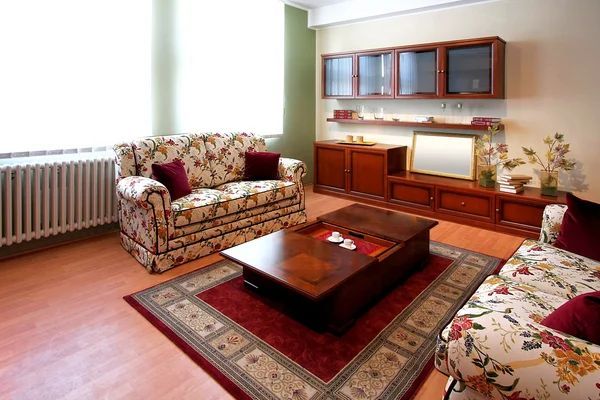 Communal living room in nursing home with traditional furniture and entertainment center.