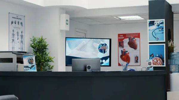 Medical clinic reception desk with health information displays and anatomical posters.