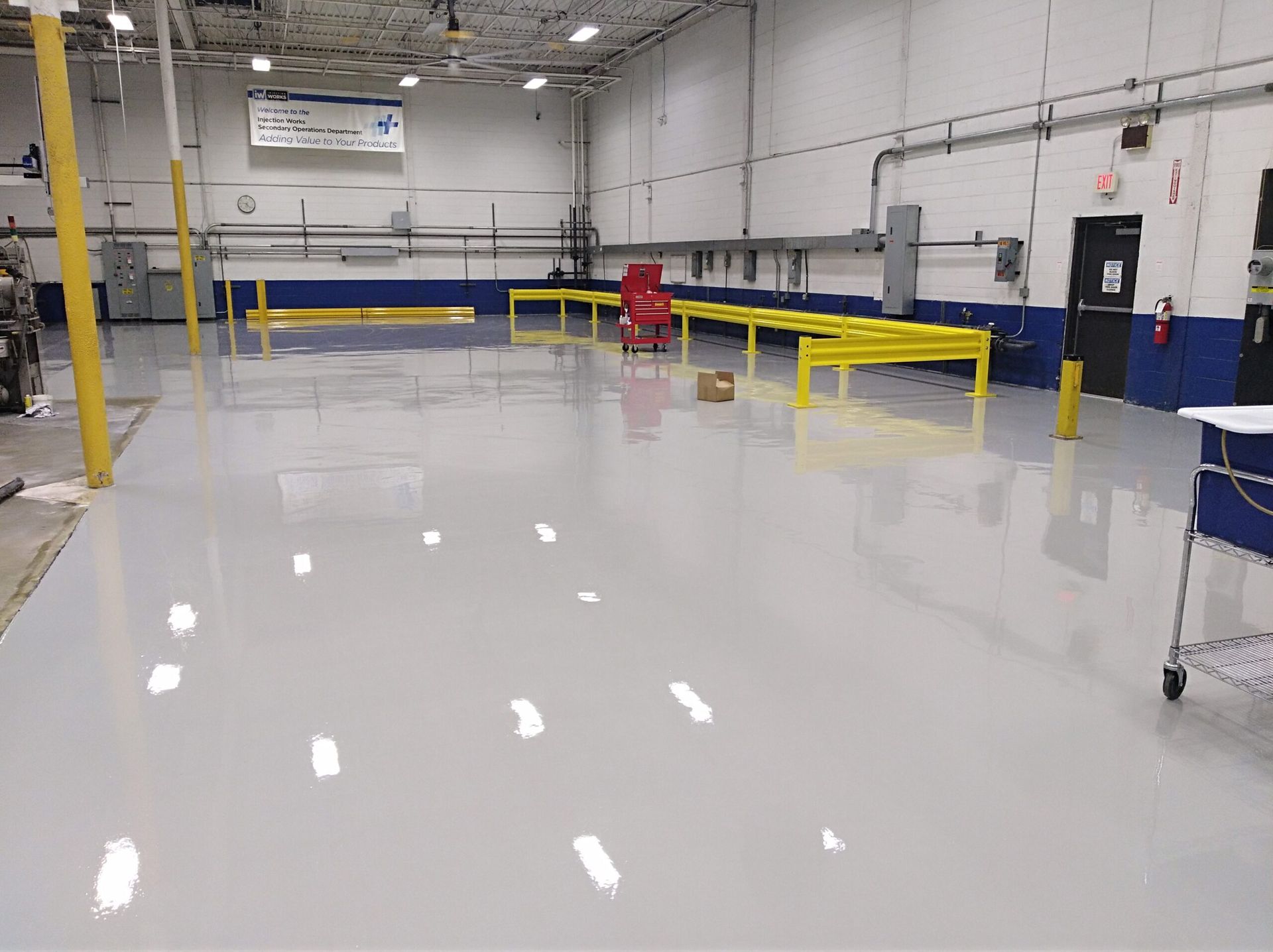 A large warehouse with a shiny floor and a red chair in the middle.