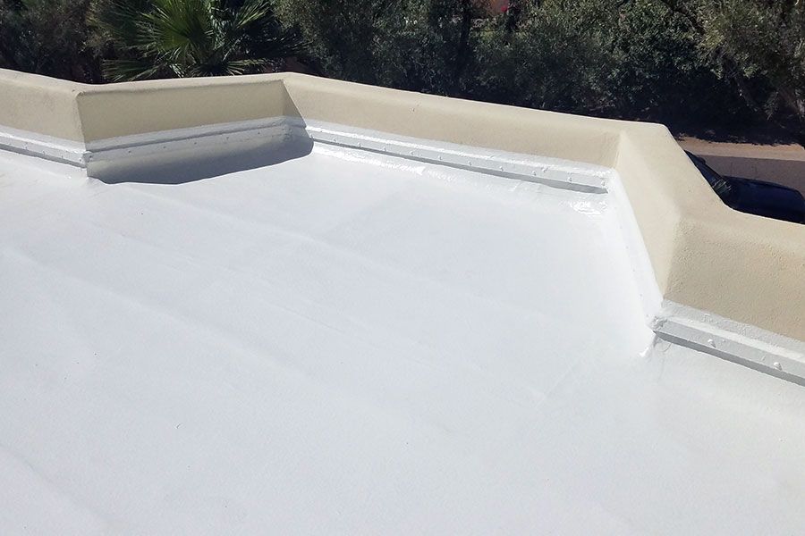 Completed acrylic roof coating on flat roof showing white reflective surface and waterproof protection.