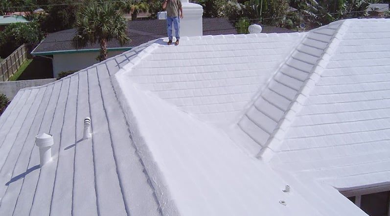 Residential tile roof with white acrylic coating showing energy-efficient reflective surface finish.