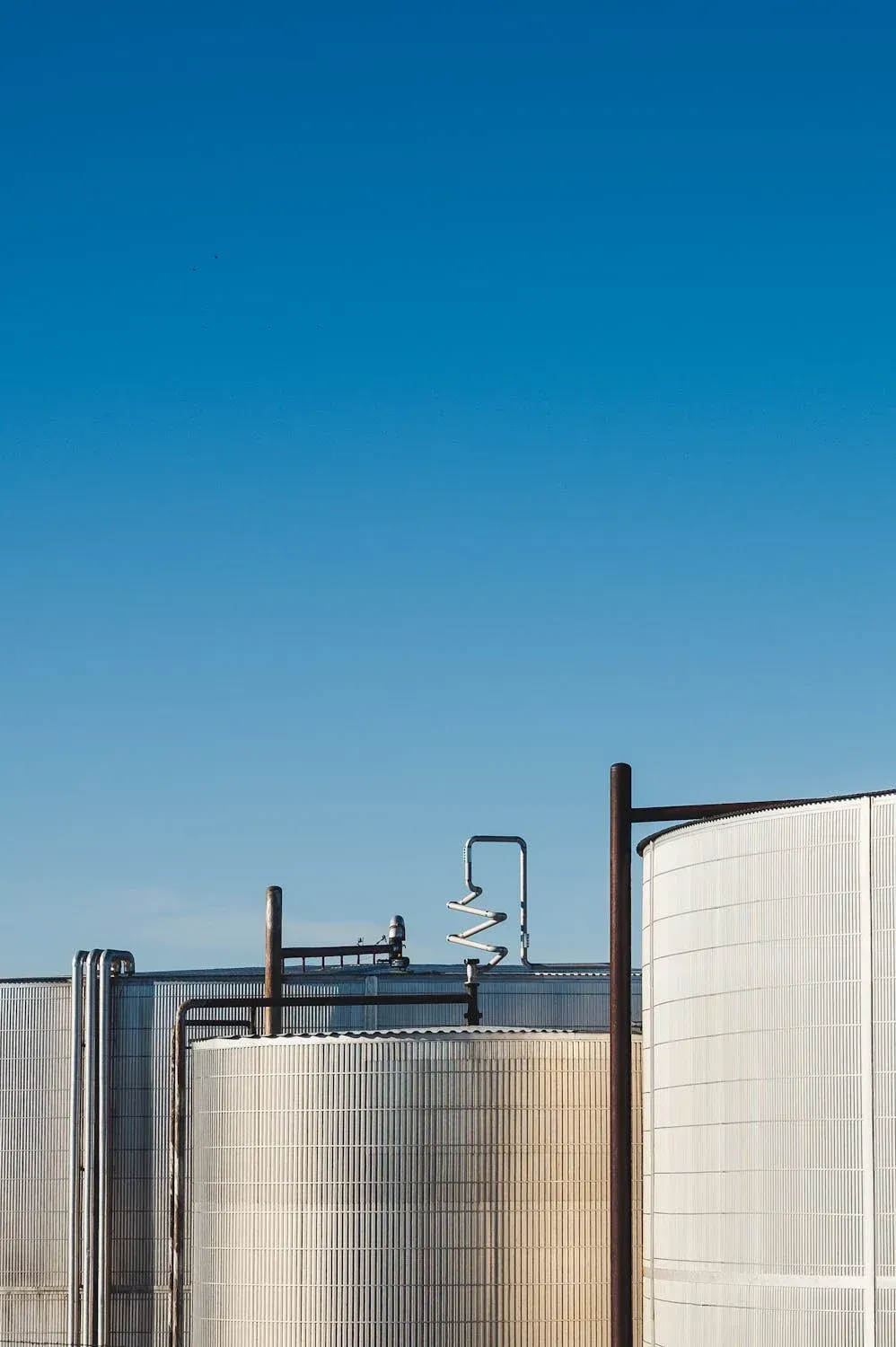 Manufacturing storage tanks with metal pipes against clear blue sky.