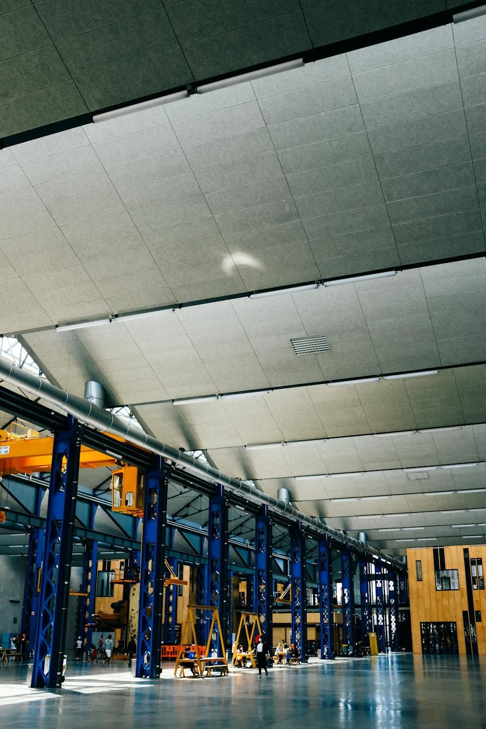 Large manufacturing facility with blue support columns and high ceiling.