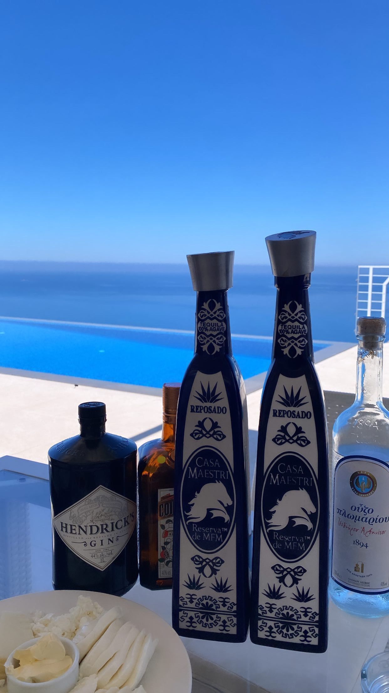 Blue bottles and white flowers on a table beside an infinity pool overlooking the ocean