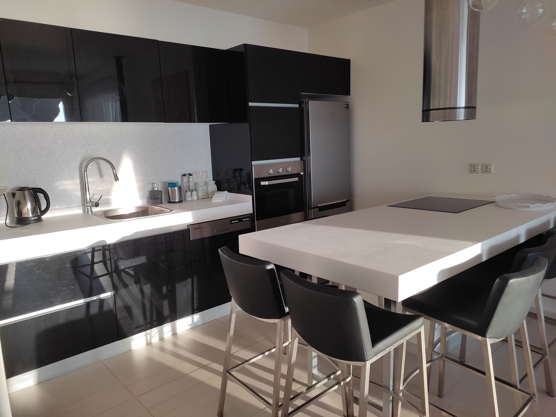 Modern kitchen with black cabinets, white island, and a dining table with chairs
