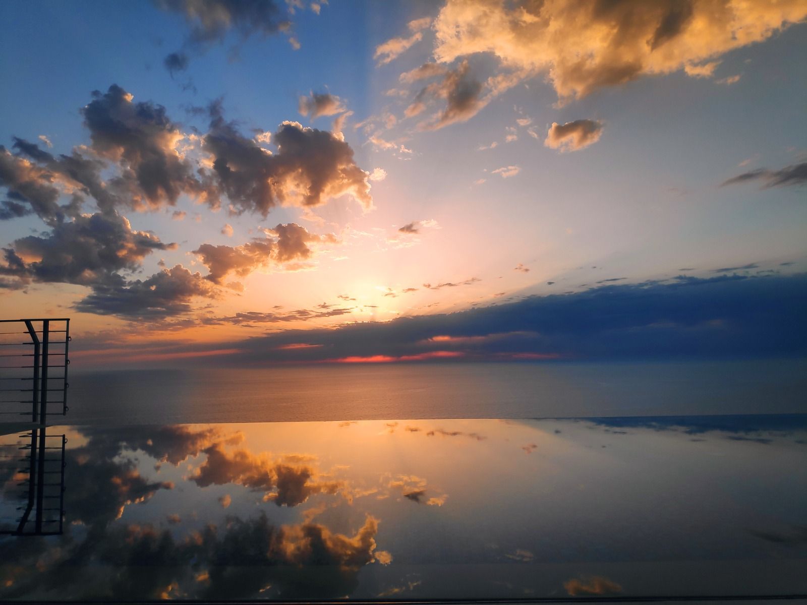 Sunset over a calm lake, with orange clouds and the sky reflected on the water.