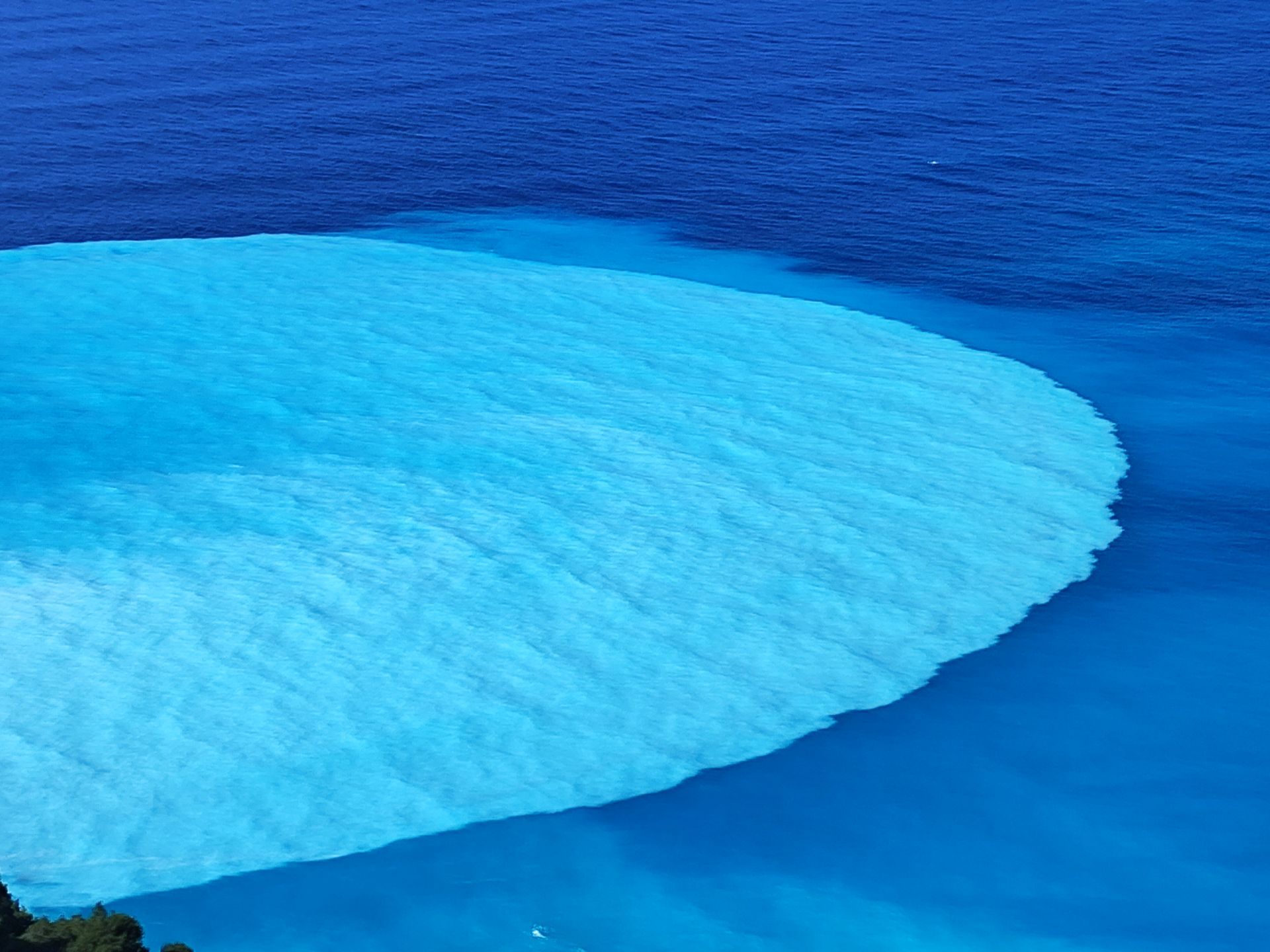 Bright turquoise ocean wave curling over deep blue water
