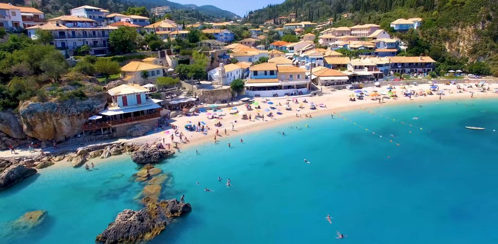 Aerial view of a crowded tropical beach with turquoise water and seaside buildings.