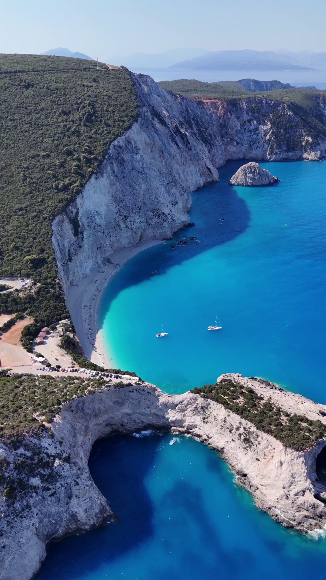 Turquoise cove beside steep white cliffs and rocky shoreline under clear sky