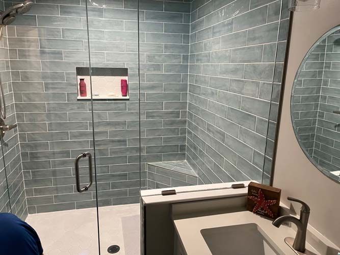Accessible bathroom with walk-in shower, tiled walls, grab bars, and vanity sink.